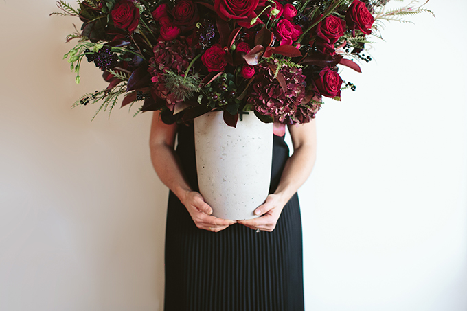 Luxe Holiday Floral Inspiration | Moody Oversized Winter Flower Arrangement in a cement vase with Black Magic Roses, Black Baccara Roses Gem and Lace Spray Garden Roses, Liqustrom, Hypericum, Allium, Lisianthus, Scabiosa, Chocolate Lace, Cotinus, Photina and Grevillea by Rebecca Dawn Design // JustineCelina.com