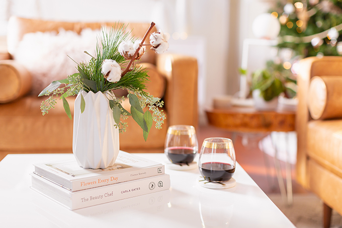 Apartment Friendly Modern Holiday Decor | Simple Holiday Arrangement on a Coffee Table with Greenery and Cotton Stems and 2 glasses of red wine with a Christmas Tree in the Background | Bohemian, Mid Century Modern Holiday Decor | Bohemian Holiday Home Tour 2018 | Canadian Tire CANVAS Ornaments // JustineCelina.com 