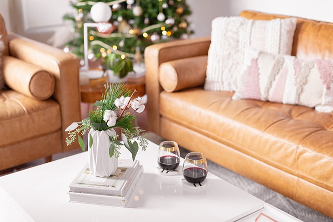 Apartment Friendly Modern Holiday Decor | Simple Holiday Arrangement on a Coffee Table with Greenery and Cotton Stems and 2 glasses of red wine with a Christmas Tree in the Background | Bohemian, Mid Century Modern Holiday Decor | Bohemian Holiday Home Tour 2018 | Canadian Tire CANVAS Ornaments // JustineCelina.com 