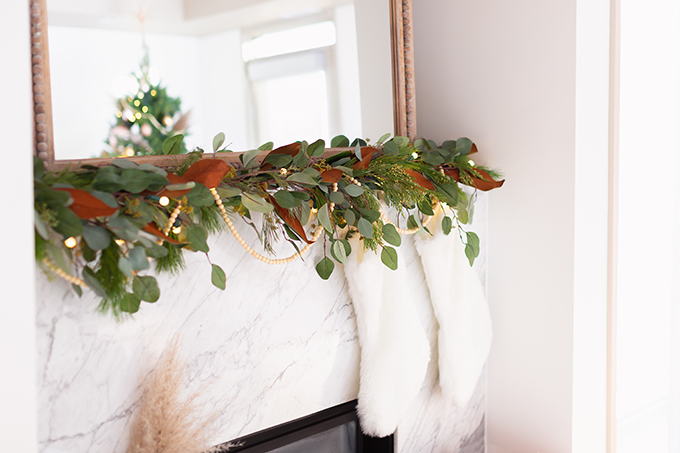 Apartment Friendly Modern Holiday Decor | Canadian Tire CANVAS Pre-lit Eucalyptus Leaves Garland with added greenery, magnolia leaves and wooden beads | Marble Fireplace | Bohemian, Mid Century Modern Holiday Decor | Bohemian Holiday Home Tour 2018 | Caramel Mid Century Modern Leather Couches | Canadian Tire CANVAS Ornaments // JustineCelina.com 