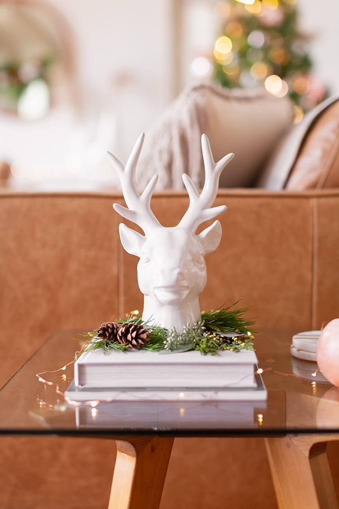Apartment Friendly Modern Holiday Decor | White Reindeer Head Sculpture with with added greenery and fairy lights | Bohemian, Mid Century Modern Holiday Decor | Bohemian Holiday Home Tour 2018 | Caramel Mid Century Modern Leather Couches | Canadian Tire CANVAS Ornaments // JustineCelina.com 