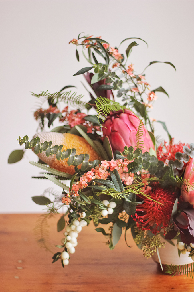 An Eclectic, Globally Inspired Arrangement featuring Euphorbia, Seeded Eucalyptus, Foraged Snowberries, Baby Blue Eucalyptus, King & Queen Protea, Leucadendron, Silver Dollar Eucalyptus, Pin Cushion, Coral Fern, Banksia | Pantone Colour of the Year 2019 Living Coral Inspiration // JustineCelina.com + Rebecca Dawn Design