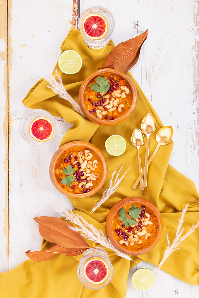 Slow Cooker Vegan Mulligatawny Soup with Red Lentils | #vegan #glutenfree | A warm bowl of vegan mulligatawny soup garnished with roasted cashews, pomegranate arils and cilantro with gold spoons and citrus water | The best vegan mulligatawny soup slow cooker recipe | vegetarian mulligatawny soup | vegetarian mulligatawny soup recipe lentils | vegetarian mulligatawny soup slow cooker | mulligatawny soup crock pot | best winter vegan slow cooker recipes // JustineCelina.com