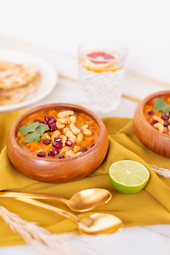 Slow Cooker Vegan Mulligatawny Soup with Red Lentils | #vegan #glutenfree | A warm bowl of vegan mulligatawny soup garnished with roasted cashews, pomegranate arils and cilantro with gold spoons and citrus water | The best vegan mulligatawny soup slow cooker recipe | vegetarian mulligatawny soup | vegetarian mulligatawny soup recipe lentils | vegetarian mulligatawny soup slow cooker | mulligatawny soup crock pot | best winter vegan slow cooker recipes // JustineCelina.com