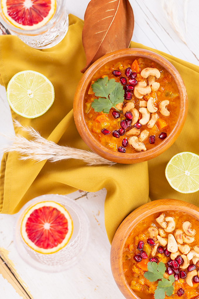 Slow Cooker Vegan Mulligatawny Soup with Red Lentils | #vegan #glutenfree | A warm bowl of vegan mulligatawny soup garnished with roasted cashews, pomegranate arils and cilantro with gold spoons and citrus water | The best vegan mulligatawny soup slow cooker recipe | vegetarian mulligatawny soup | vegetarian mulligatawny soup recipe lentils | vegetarian mulligatawny soup slow cooker | mulligatawny soup crock pot | best winter vegan slow cooker recipes // JustineCelina.com