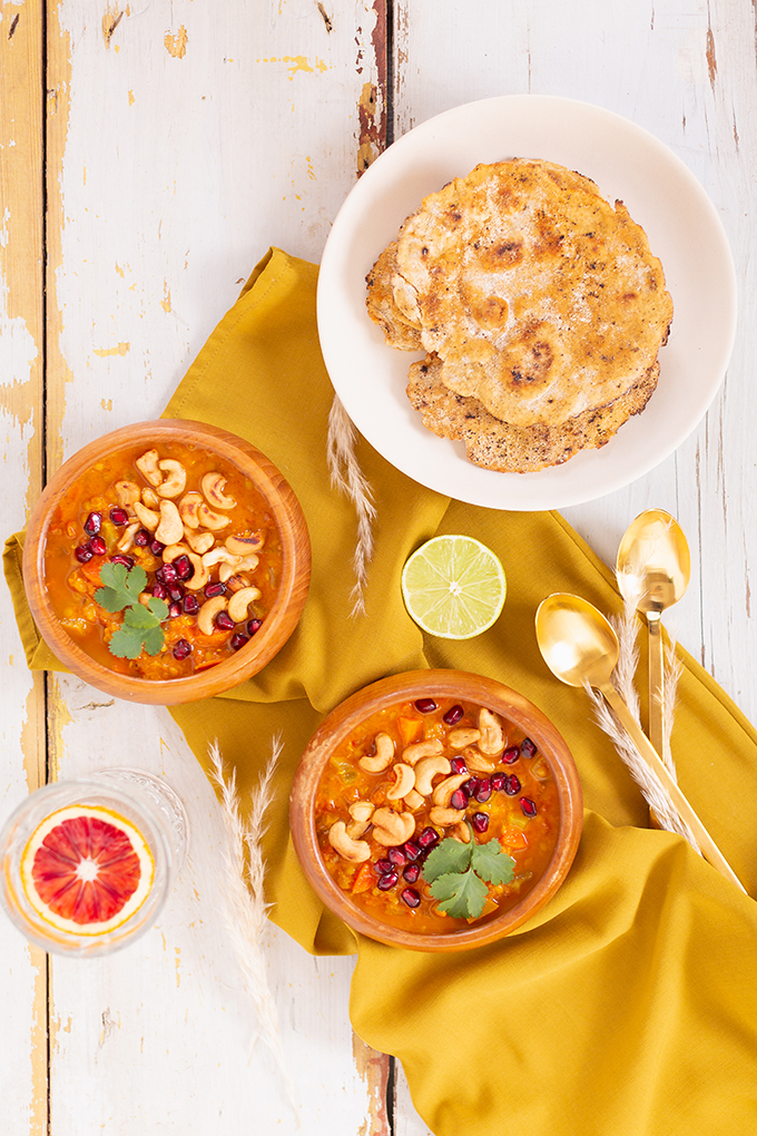 Slow Cooker Vegan Mulligatawny Soup with Red Lentils | #vegan #glutenfree | A warm bowl of vegan mulligatawny soup garnished with roasted cashews, pomegranate arils and cilantro with gold spoons and citrus water | The best vegan mulligatawny soup slow cooker recipe | vegetarian mulligatawny soup | vegetarian mulligatawny soup recipe lentils | vegetarian mulligatawny soup slow cooker | mulligatawny soup crock pot | best winter vegan slow cooker recipes // JustineCelina.com