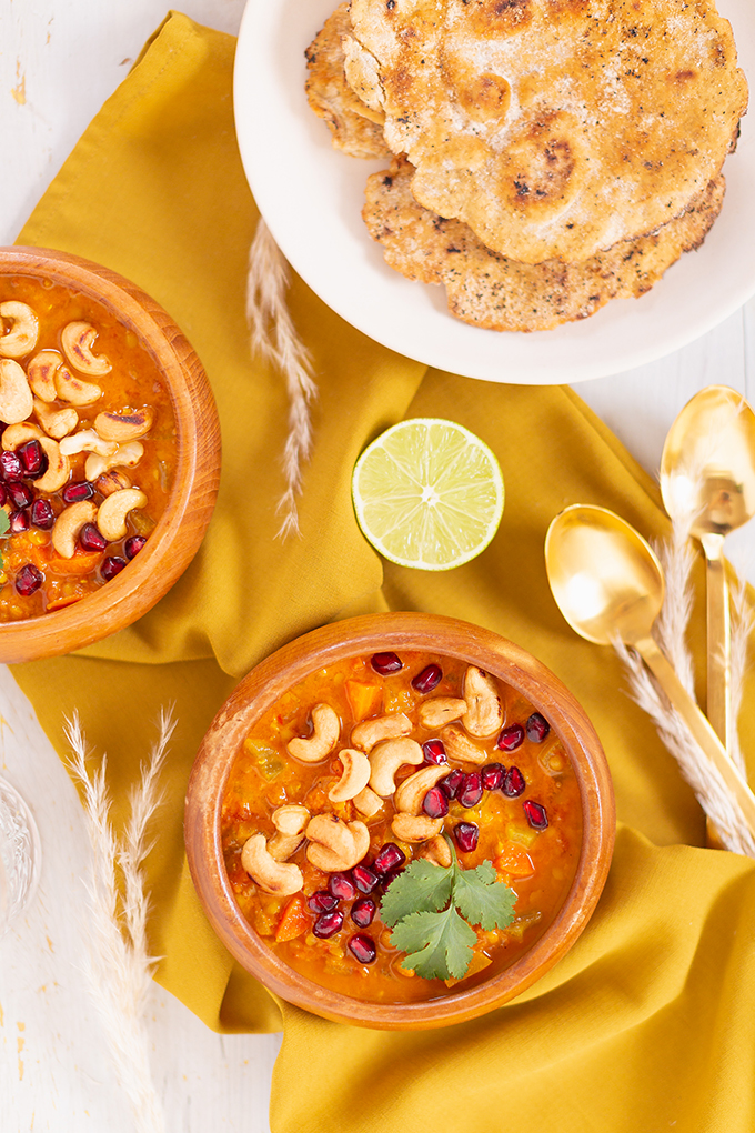 Slow Cooker Vegan Mulligatawny Soup with Red Lentils | #vegan #glutenfree | A warm bowl of vegan mulligatawny soup garnished with roasted cashews, pomegranate arils and cilantro with gold spoons and citrus water | The best vegan mulligatawny soup slow cooker recipe | vegetarian mulligatawny soup | vegetarian mulligatawny soup recipe lentils | vegetarian mulligatawny soup slow cooker | mulligatawny soup crock pot | best winter vegan slow cooker recipes // JustineCelina.com