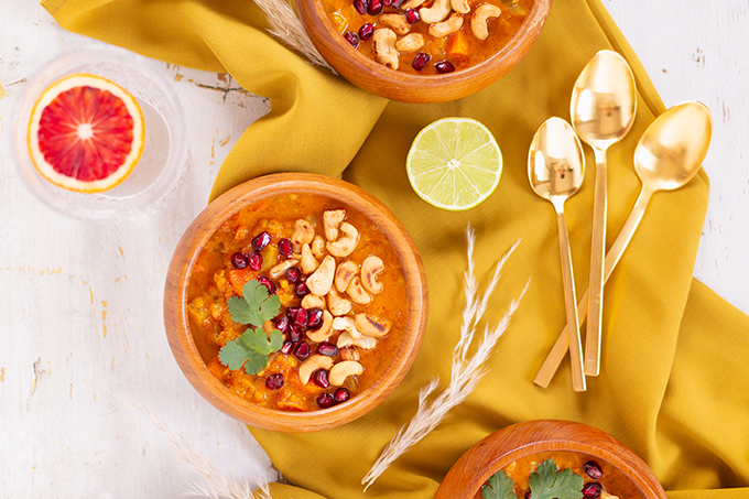 Slow Cooker Vegan Mulligatawny Soup with Red Lentils | #vegan #glutenfree | A warm bowl of vegan mulligatawny soup garnished with roasted cashews, pomegranate arils and cilantro with gold spoons and citrus water | The best vegan mulligatawny soup slow cooker recipe | vegetarian mulligatawny soup | vegetarian mulligatawny soup recipe lentils | vegetarian mulligatawny soup slow cooker | mulligatawny soup crock pot | best winter vegan slow cooker recipes // JustineCelina.com