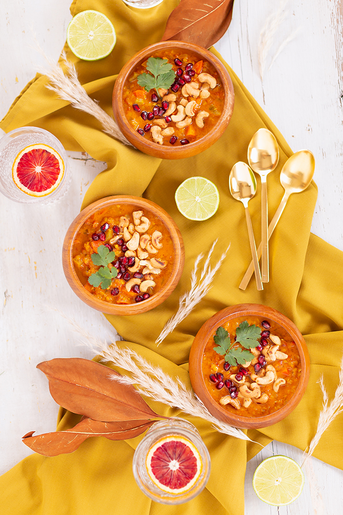 Slow Cooker Vegan Mulligatawny Soup with Red Lentils | #vegan #glutenfree | A warm bowl of vegan mulligatawny soup garnished with roasted cashews, pomegranate arils and cilantro with gold spoons and citrus water | The best vegan mulligatawny soup slow cooker recipe | vegetarian mulligatawny soup | vegetarian mulligatawny soup recipe lentils | vegetarian mulligatawny soup slow cooker | mulligatawny soup crock pot | best winter vegan slow cooker recipes // JustineCelina.com