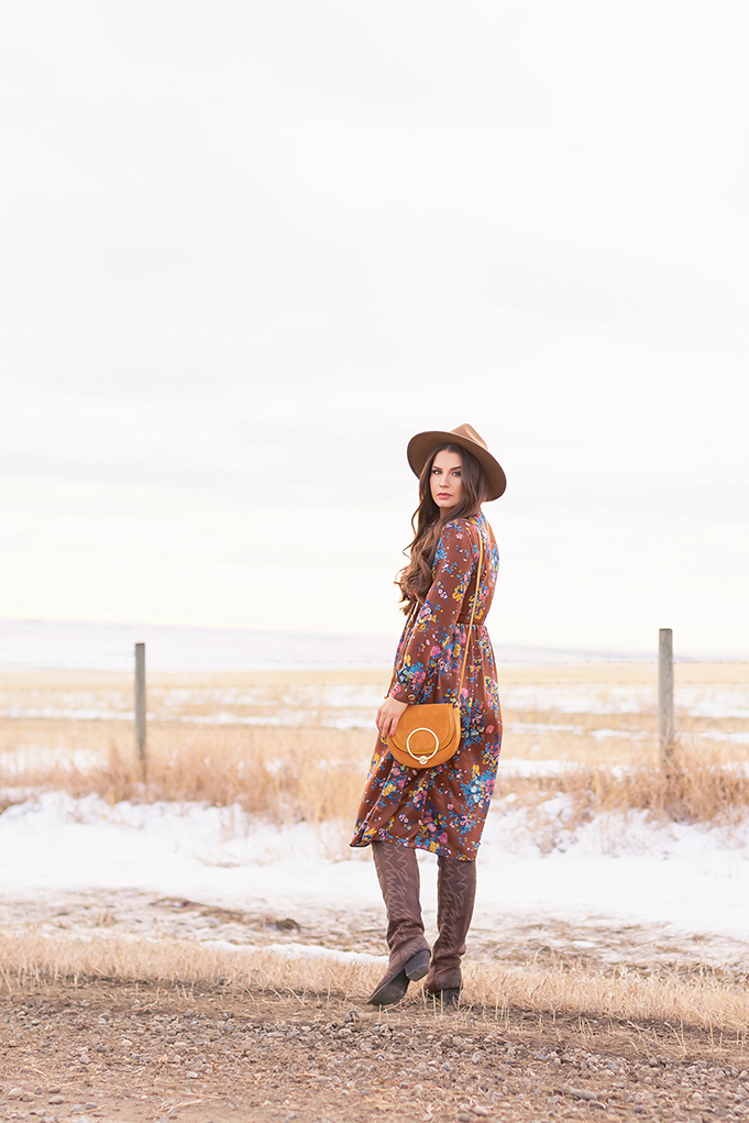 Pre Spring 2019 Trend Guide Bohemian Rhapsody: How to Style Midi Dresses for Transitional Spring Weather | Brunette Girl Standing in a Country Field at Sunrise Wearing a Brown Floral Dress, Brown Wide Brim Hat and a Mustard Cross Body Bag | Bohemian Winter Style Ideas | Pantone Spring Summer 2019 Fashion Ideas | Calgary, Alberta, Canada Fashion & Lifestyle Blogger // JustineCelina.com