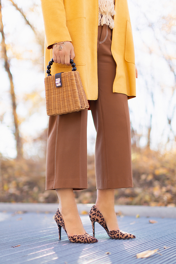 WORK WEAR | SPRING 2019 TRENDS AT THE OFFICE | How to Style Culottes for the Office | Brown 70’s Style Culottes with a Mustard Faux Suede Jacket, Knit Fringe Hem Top, Natural Material Rattan Woven Box Bag and Leopard Print D’Orsay Heels | Spring 2019 Trends | Office Appropriate Spring Outfit Ideas // JustineCelina.com