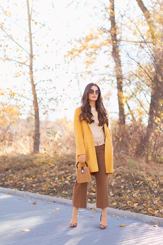 WORK WEAR | SPRING 2019 TRENDS AT THE OFFICE | How to Style Culottes for the Office | Brown 70’s Style Culottes with a Mustard Faux Suede Jacket, Knit Fringe Hem Top, Natural Material Rattan Woven Box Bag and Leopard Print D’Orsay Heels | Spring 2019 Trends | Office Appropriate Spring Outfit Ideas // JustineCelina.com