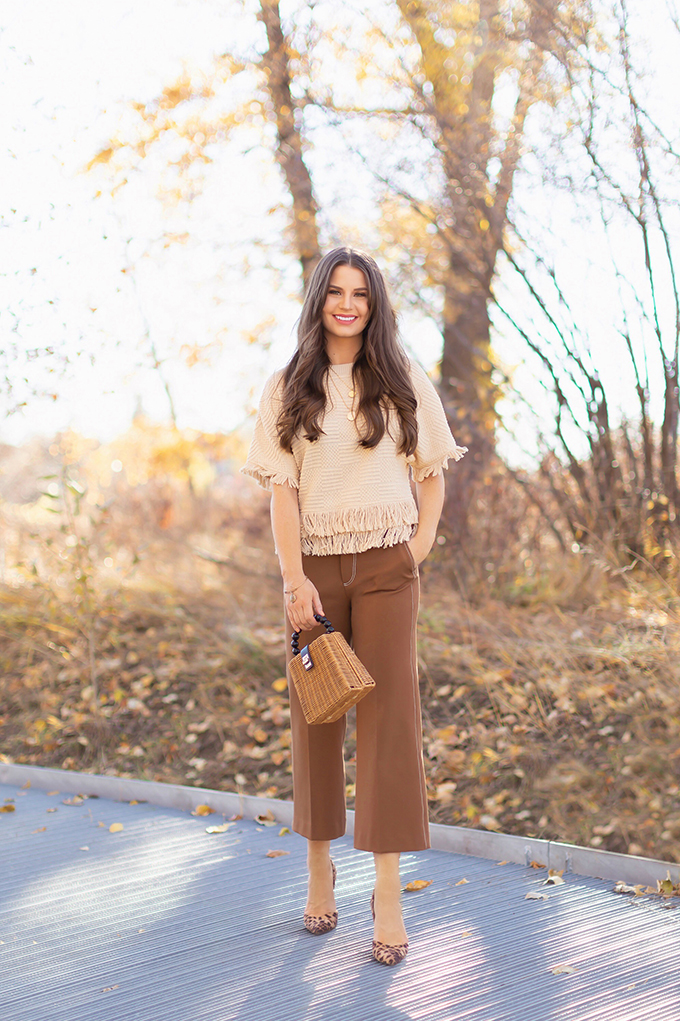 WORK WEAR | SPRING 2019 TRENDS AT THE OFFICE | How to Style Culottes for the Office | Brown 70’s Style Culottes with a Mustard Faux Suede Jacket, Knit Fringe Hem Top, Natural Material Rattan Woven Box Bag and Leopard Print D’Orsay Heels | Spring 2019 Trends | Office Appropriate Spring Outfit Ideas // JustineCelina.com