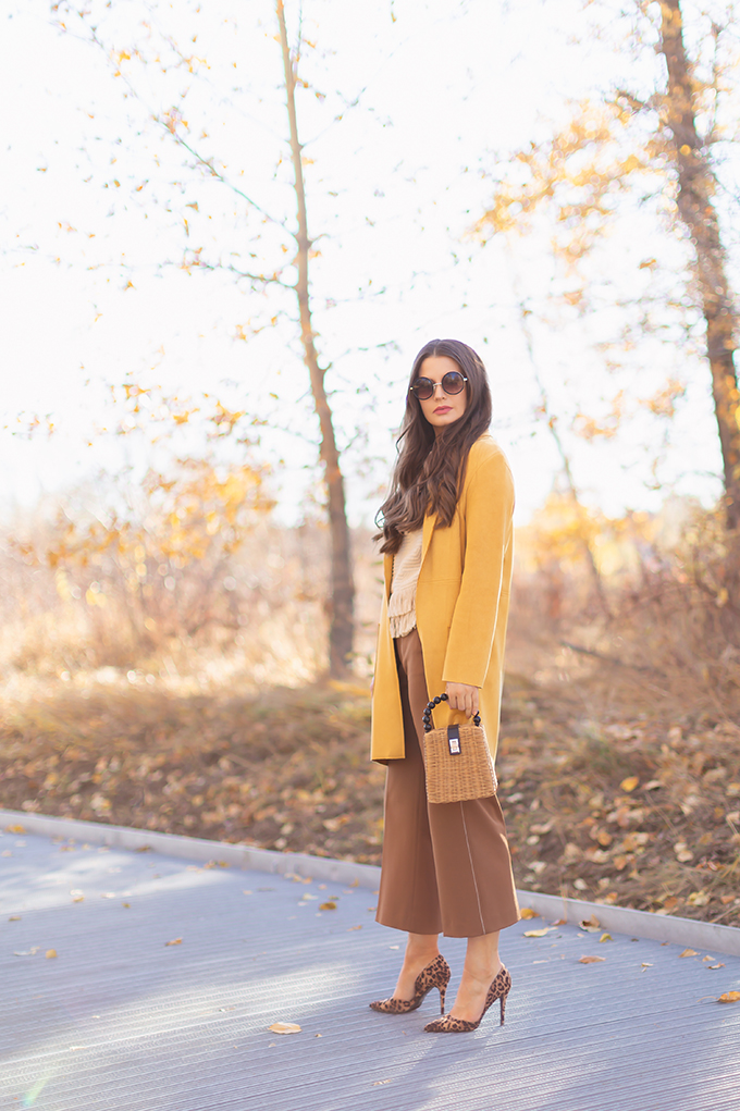WORK WEAR | SPRING 2019 TRENDS AT THE OFFICE | How to Style Culottes for the Office | Brown 70’s Style Culottes with a Mustard Faux Suede Jacket, Knit Fringe Hem Top, Natural Material Rattan Woven Box Bag and Leopard Print D’Orsay Heels | Spring 2019 Trends | Office Appropriate Spring Outfit Ideas // JustineCelina.com