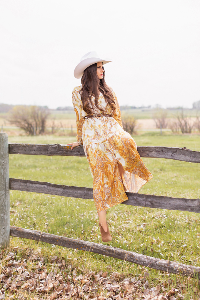 How to Style | Calgary’s White Hat for The Stampede | Stampede 2019 Outfit Ideas | Brunette Woman wearing a flow Paisley dress with a vintage western belt, Smithbilt The White Hat in White Felt and mid heel ankle boots with a round rattan bag | Smithbilt White Hat Outfit | How to Style a Cowboy Hat for the Calgary Stampede | Calgary Stampede Dress Code | Bohemian Western Inspired Outfit Summer 2019 | Boho Stampede Style | Justine Celina Maguire x Tourism Calgary // JustineCelina.com