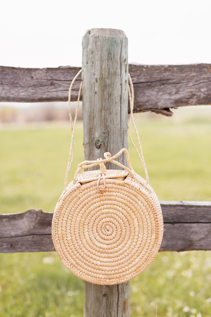 How to Style | Calgary’s White Hat for The Stampede | A round rattan bag hanging on a western wooden fence in the country | Calgary Stampede Dress Code | Bohemian Western Inspired Outfit Summer 2019 | Boho Stampede Style | Justine Celina Maguire x Tourism Calgary // JustineCelina.com