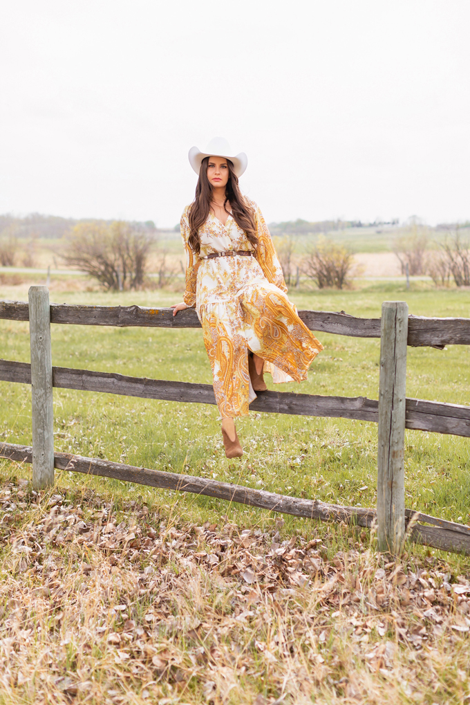 How to Style | Calgary’s White Hat for The Stampede | Stampede 2019 Outfit Ideas | Brunette Woman wearing a flow Paisley dress with a vintage western belt, Smithbilt The White Hat in White Felt and mid heel ankle boots with a round rattan bag | Smithbilt White Hat Outfit | How to Style a Cowboy Hat for the Calgary Stampede | Calgary Stampede Dress Code | Bohemian Western Inspired Outfit Summer 2019 | Boho Stampede Style | Justine Celina Maguire x Tourism Calgary // JustineCelina.com