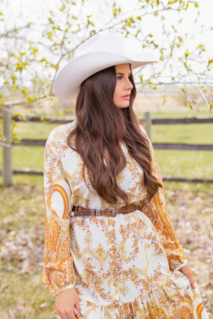 How to Style | Calgary’s White Hat for The Stampede | Stampede 2019 Outfit Ideas | Brunette Woman wearing a flow Paisley dress with a vintage western belt, Smithbilt The White Hat in White Felt and mid heel ankle boots with a round rattan bag | Smithbilt White Hat Outfit | How to Style a Cowboy Hat for the Calgary Stampede | Calgary Stampede Dress Code | Bohemian Western Inspired Outfit Summer 2019 | Boho Stampede Style | Justine Celina Maguire x Tourism Calgary // JustineCelina.com