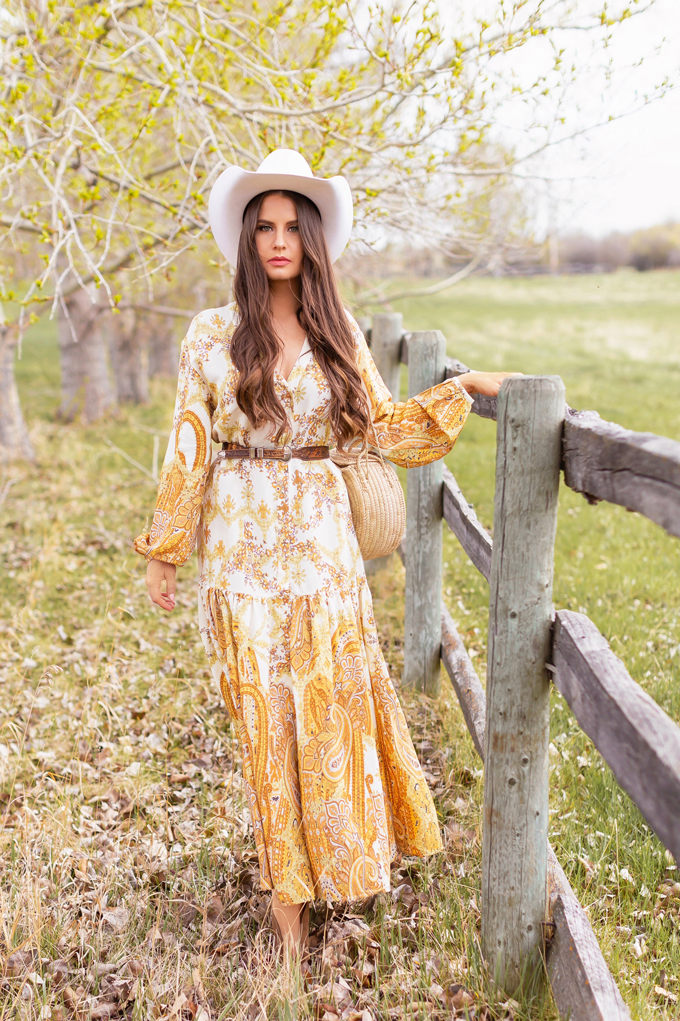 How to Style | Calgary’s White Hat for The Stampede | Stampede 2019 Outfit Ideas | Brunette Woman wearing a flow Paisley dress with a vintage western belt, Smithbilt The White Hat in White Felt and mid heel ankle boots with a round rattan bag | Smithbilt White Hat Outfit | How to Style a Cowboy Hat for the Calgary Stampede | Calgary Stampede Dress Code | Bohemian Western Inspired Outfit Summer 2019 | Boho Stampede Style | Justine Celina Maguire x Tourism Calgary // JustineCelina.com