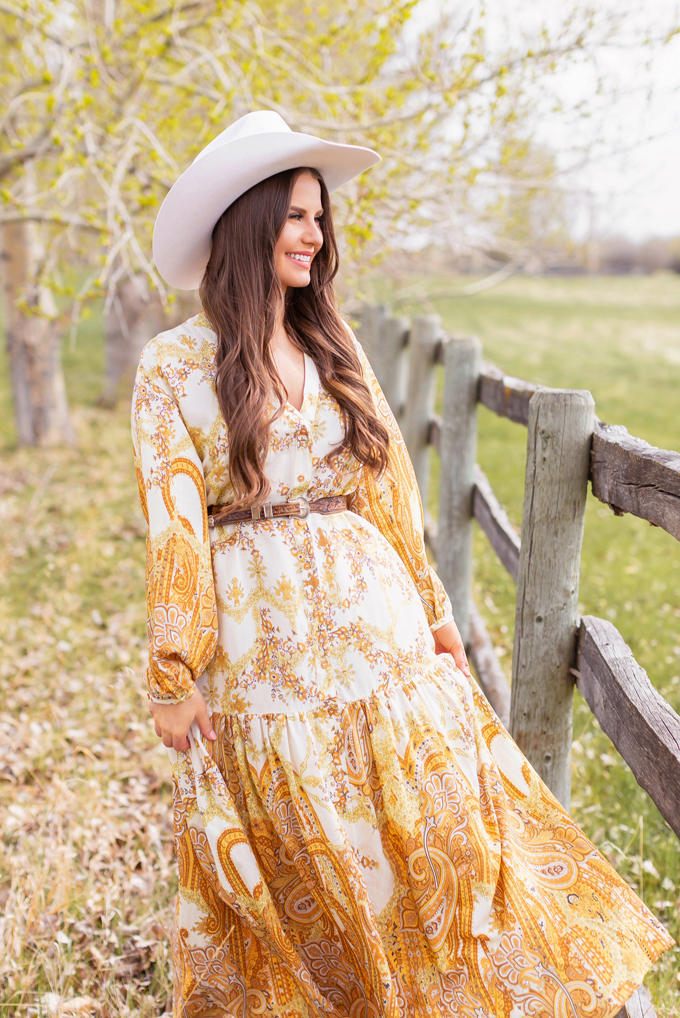 How to Style | Calgary’s White Hat for The Stampede | Stampede 2019 Outfit Ideas | Brunette Woman wearing a flow Paisley dress with a vintage western belt, Smithbilt The White Hat in White Felt and mid heel ankle boots with a round rattan bag | Smithbilt White Hat Outfit | How to Style a Cowboy Hat for the Calgary Stampede | Calgary Stampede Dress Code | Bohemian Western Inspired Outfit Summer 2019 | Boho Stampede Style | Justine Celina Maguire x Tourism Calgary // JustineCelina.com