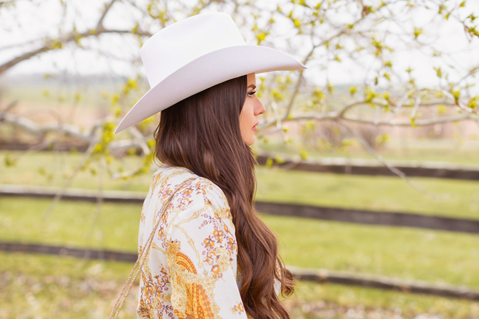 How to Style | Calgary’s White Hat for The Stampede | Stampede 2019 Outfit Ideas | Brunette Woman wearing a flow Paisley dress with a vintage western belt, Smithbilt The White Hat in White Felt and mid heel ankle boots with a round rattan bag | Smithbilt White Hat Outfit | How to Style a Cowboy Hat for the Calgary Stampede | Calgary Stampede Dress Code | Bohemian Western Inspired Outfit Summer 2019 | Boho Stampede Style | Justine Celina Maguire x Tourism Calgary // JustineCelina.com