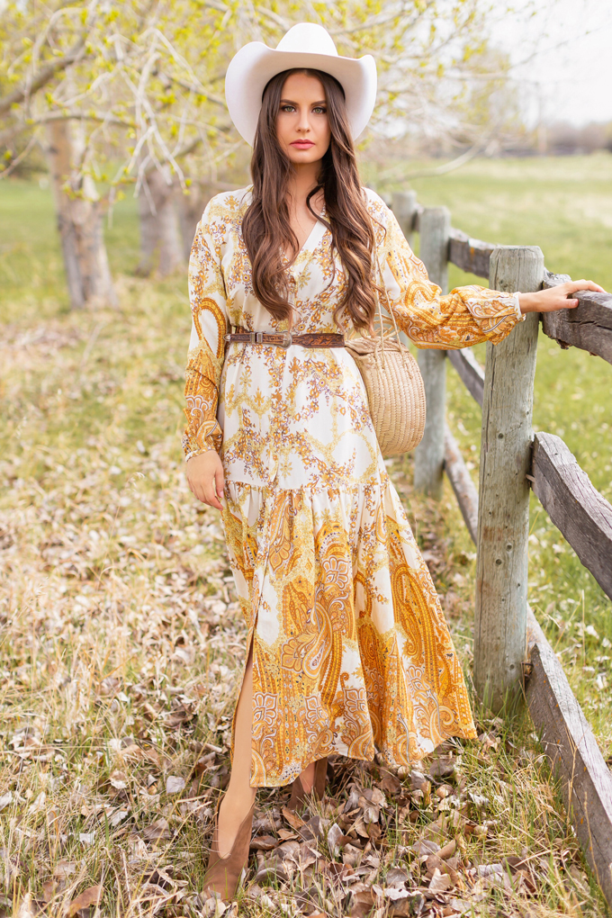 How to Style | Calgary’s White Hat for The Stampede | Stampede 2019 Outfit Ideas | Brunette Woman wearing a flow Paisley dress with a vintage western belt, Smithbilt The White Hat in White Felt and mid heel ankle boots with a round rattan bag | Smithbilt White Hat Outfit | How to Style a Cowboy Hat for the Calgary Stampede | Calgary Stampede Dress Code | Bohemian Western Inspired Outfit Summer 2019 | Boho Stampede Style | Justine Celina Maguire x Tourism Calgary // JustineCelina.com