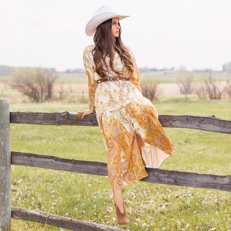 How to Style | Calgary’s White Hat for The Stampede | Stampede 2019 Outfit Ideas | Brunette Woman wearing a flow Paisley dress with a vintage western belt, Smithbilt The White Hat in White Felt and mid heel ankle boots with a round rattan bag | Smithbilt White Hat Outfit | How to Style a Cowboy Hat for the Calgary Stampede | Calgary Stampede Dress Code | Bohemian Western Inspired Outfit Summer 2019 | Boho Stampede Style | Justine Celina Maguire x Tourism Calgary // JustineCelina.com