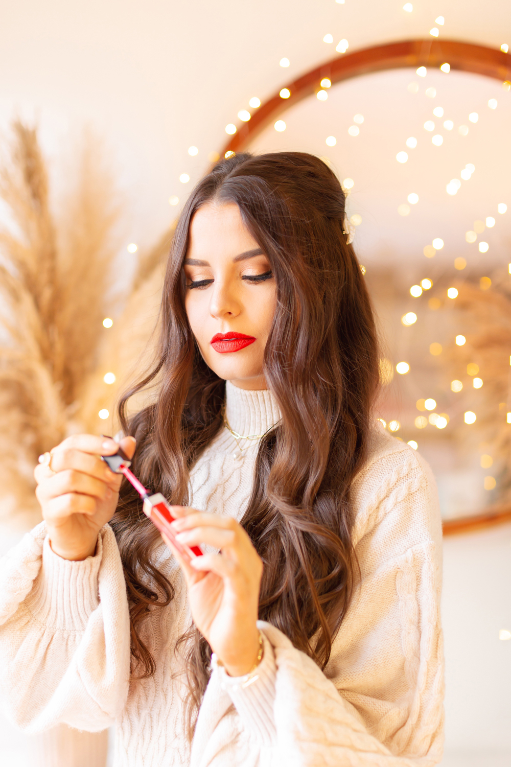 My Top 5 Red Lipsticks for the Holidays | Clove + Hallow Lip Velvet in Fiesta photos, review, swatches | Brunette woman wearing a red lipstick and cable kit sweater dress in a festive holiday setting with bokeh lights | Best clean vegan red lipstick | Best carmine free red lipstick | Best Vegan Lipstick for the Holidays | Best red liquid lipstick | Best long lasting red lipstick | Christmas lipstick 2021 | Mask friendly red lipstick | Calgary Beauty Blogger // JustineCelina.com