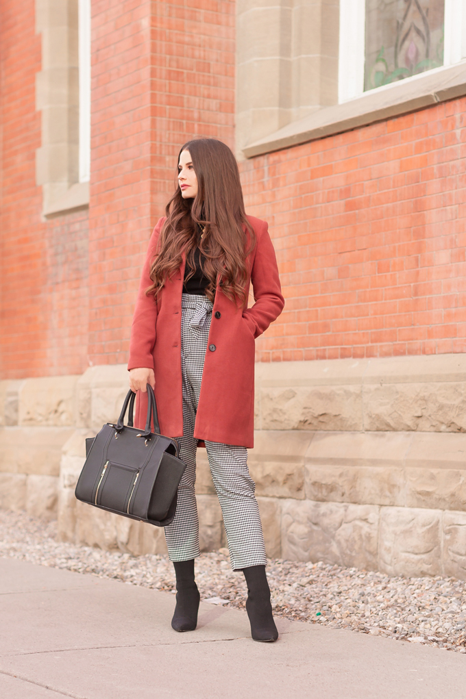 WINTER / SPRING 2020 LOOKBOOK | Boss Babe | Brunette woman wearing a Vero Moda Rust Dress Coat, H&M Houndstooth Paperbag Pants, Black Saks 5th Avenue Cashmere Turtleneck, Lulus Back Wing Woman Handbag and Zara Black Sock Boots | Professional Winter to Spring Outfit Ideas | Top Transitional Winter to Spring 2020 Trends | Canadian Winter / Spring Lookbook | How to Wear Spring 2020’s Mini Dress | Transitional Winter to Spring Fashion for Canadians // JustineCelina.com