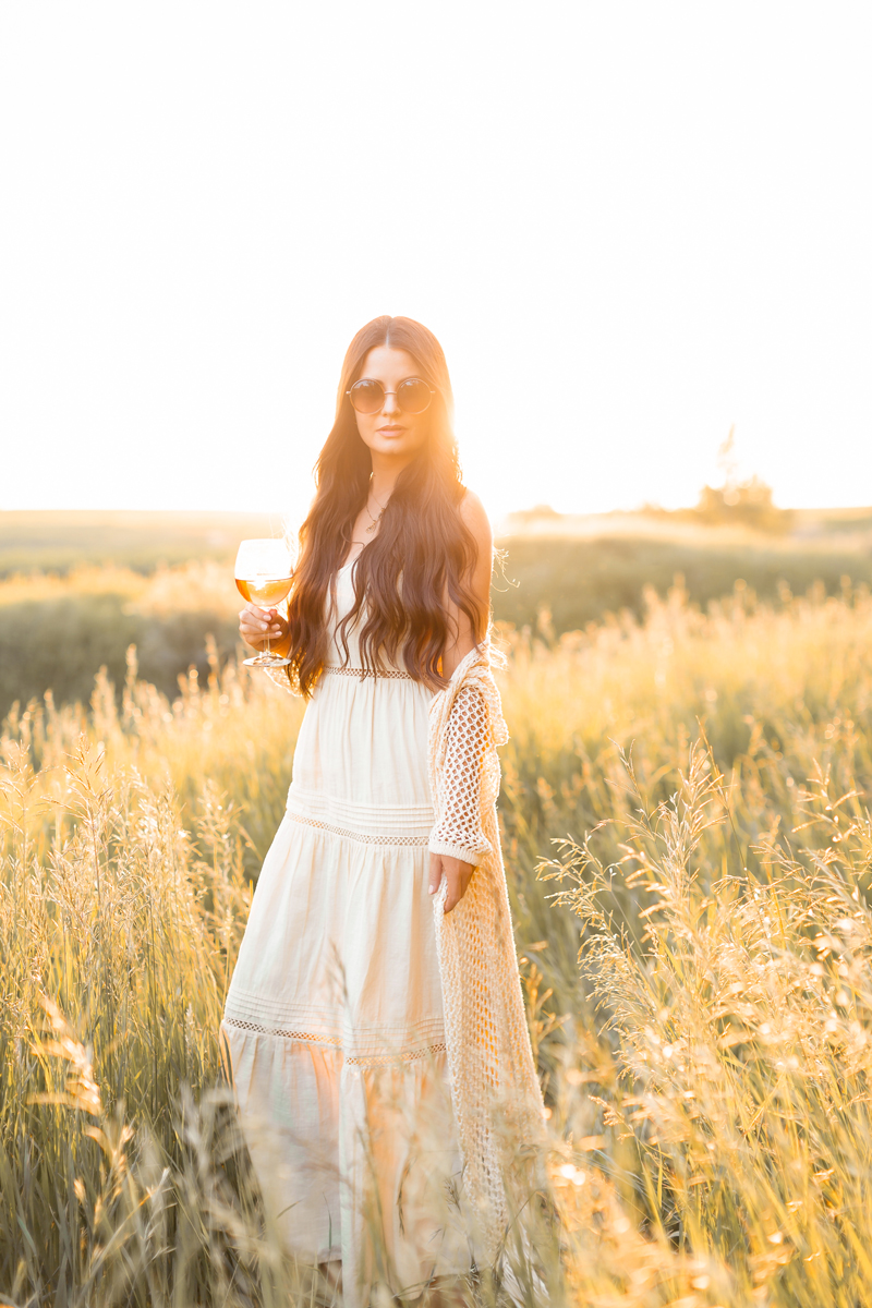 Summer 2020 Lookbook | Boho Summer 2020 Outfit Ideas | Brunette woman wearing a yellow maxi dress and crochet cardigan enjoying a glass of rosé wine in a sunlit prairie wheat field at sunset | JustineCelina’s childhood home in Wheatland County, Alberta | Summer 2020 Bohemian Style Ideas | Boho Casual Summer Dresses | Summer 2020 Fashion | Best H&M Dresses Summer 2020 | H&M V-neck Cotton Dress in Light Yellow | Calgary, Alberta, Canada Creative Lifestyle Blogger // JustineCelina.com