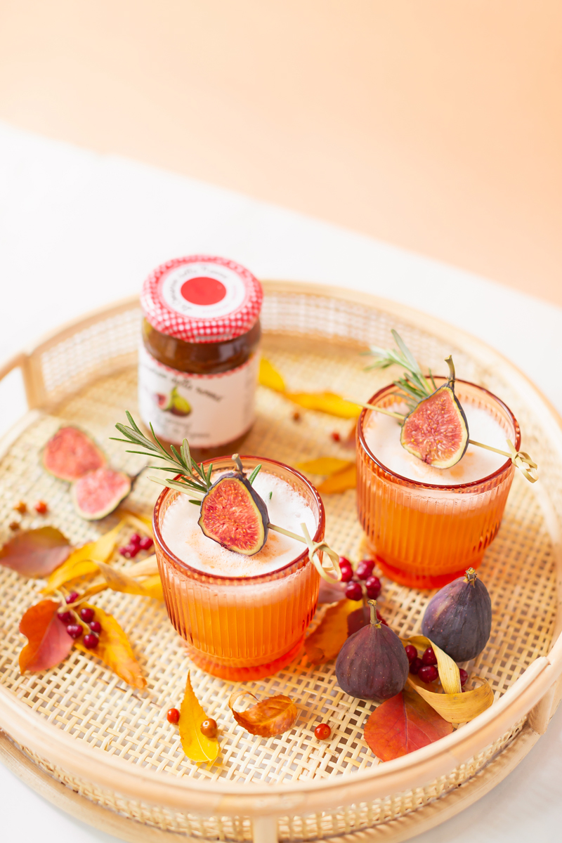 Rosemary Fig Japanese Whisky Sour | A Whisky Sour Cocktail with a Fresh Fig Garnish on a Rattan Serving Tray with Autumn Leaves and a jar of Fig Preserves in the Background | Autumn Whiskey Cocktails | Best Fall Whisky Cocktail Recipes | Fall Fig Cocktail | Fall Summer Cocktail | Fig Cocktail Syrup | Japanese Whisky Cocktail | Nikka Super Rare Old Cocktail | Nikka Cocktail | Whiskey Sour With Egg | Calgary Cocktail Photographer and Stylist | Calgary Lifestyle Blogger // JustineCelina.com