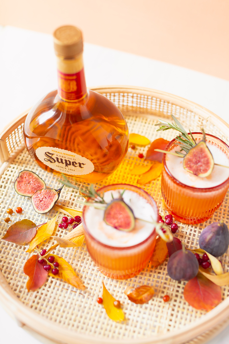 Rosemary Fig Japanese Whisky Sour | Nikka Super Rare Old Japanese Whisky with Autumn Leaves and Rerries on a Rattan Serving Tray against a soft Orange Background | Autumn Whiskey Cocktails | Best Fall Whisky Cocktail Recipes | Fall Fig Cocktail | Fall Summer Cocktail | Japanese Whisky Cocktail | Nikka Super Rare Old Cocktail | Nikka Cocktail | Nikka Super Rare Old Review | Whiskey Sour With Egg | Calgary Cocktail Photographer and Stylist | Calgary Lifestyle Blogger // JustineCelina.com