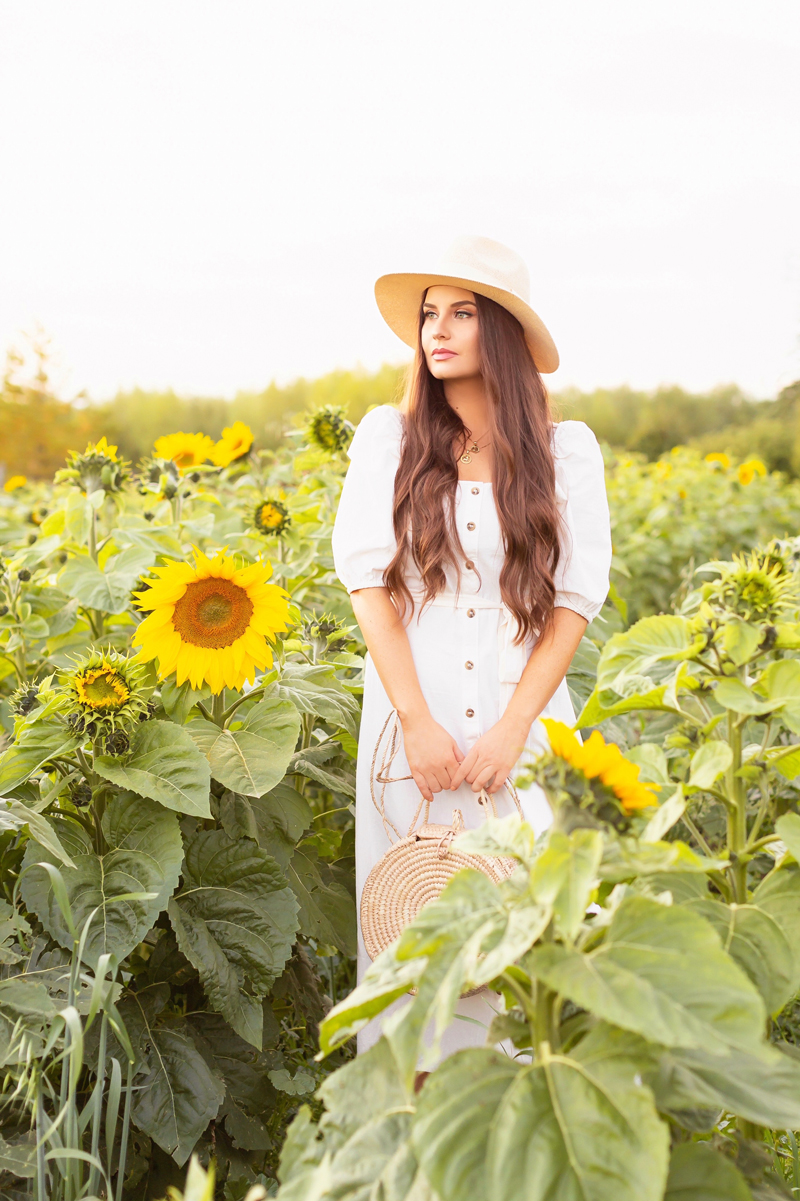 A Guide to Bowden SunMaze & Eagle Creek Farms | Bowden SunMaze September 2020 | Sunflower Field Near Me | The Best Alberta Sunflower Field | Alberta Sunflower U-Pick | Bowden SunMaze Sunflower Field Best Time To Go | Bowden SunMaze Cost | Eagle Creek Farms Review | Sunflower Field Photography Tips | Cottagecore Aesthetic | Brunette woman wearing a cream Crêped Cotton Dress and woven fedora in a field of sunflowers at sunset | Calgary Lifestyle Blogger // JustineCelina.com