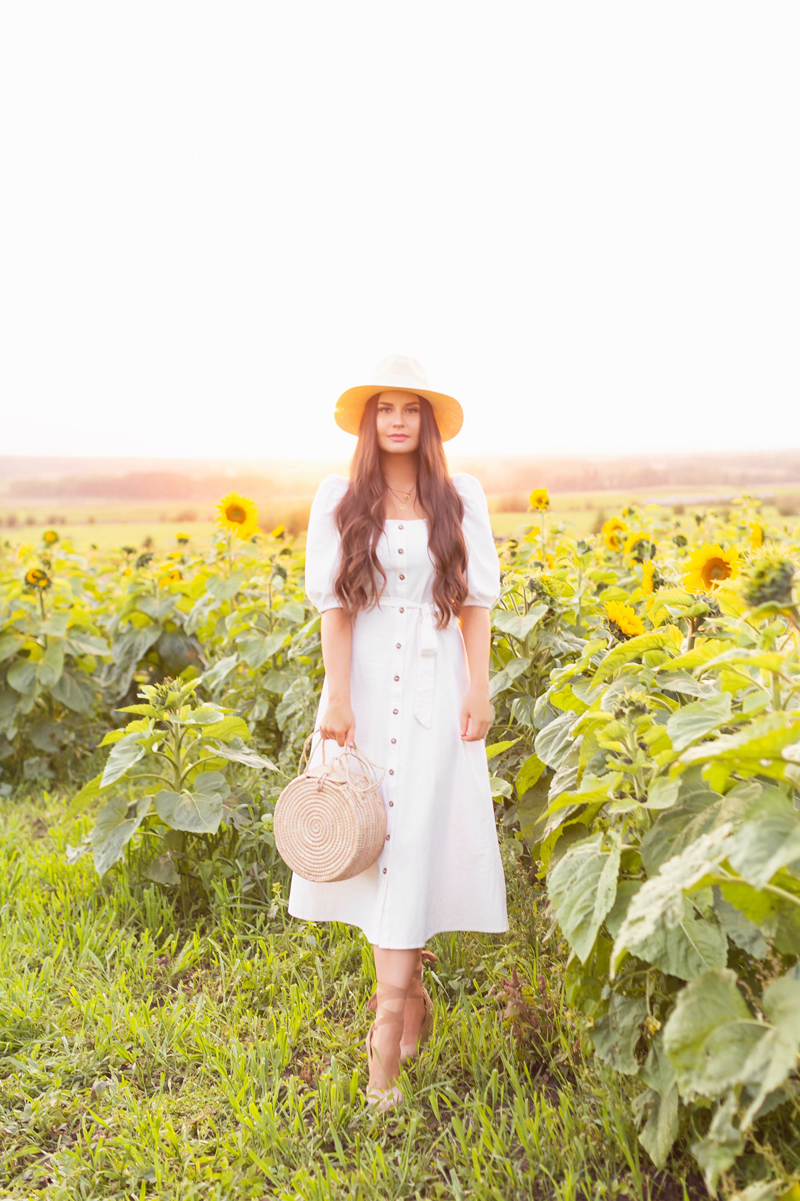 A Guide to Bowden SunMaze & Eagle Creek Farms | Bowden SunMaze September 2020 | Sunflower Field Near Me | The Best Alberta Sunflower Field | Alberta Sunflower U-Pick | Bowden SunMaze Sunflower Field Best Time To Go | Bowden SunMaze Cost | Eagle Creek Farms Review | Sunflower Field Photography Tips | Cottagecore Outfit | Brunette woman wearing a cream Crêped Cotton Dress and woven fedora laughing in a field of sunflowers at sunset | Calgary Lifestyle Blogger // JustineCelina.com