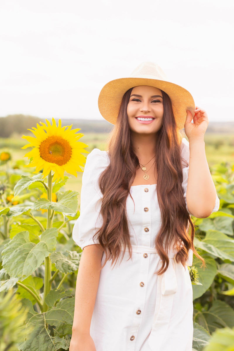 A Guide to Bowden SunMaze & Eagle Creek Farms | Bowden SunMaze September 2020 | Sunflower Field Near Me | The Best Alberta Sunflower Field | Alberta Sunflower U-Pick | Bowden SunMaze Sunflower Field Best Time To Go | Bowden SunMaze Cost | Eagle Creek Farms Review | Sunflower Field Instagram Tips | Cottagecore Aesthetic | Smiling brunette woman wearing a cream Crêped Cotton Dress and woven fedora laughing in a field of sunflowers at sunset | Calgary Lifestyle Blogger // JustineCelina.com