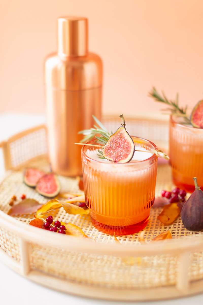 Rosemary Fig Japanese Whisky Sour | A Whisky Sour Cocktail with a Fresh Fig Garnish on a Rattan Serving Tray with Autumn Leaves and a Brass Cocktail Shaker in the Background | Autumn Whiskey Cocktails | Best Fall Whisky Cocktail Recipes | Fall Fig Cocktail | Fall Summer Cocktail | Fig Cocktail Syrup | Japanese Whisky Cocktail | Nikka Super Rare Old Cocktail | Nikka Cocktail | Whiskey Sour With Egg | Calgary Cocktail Photographer and Stylist | Calgary Lifestyle Blogger // JustineCelina.com