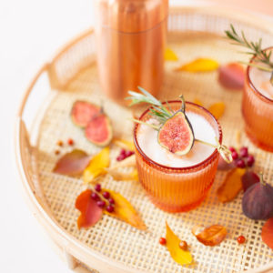 Rosemary Fig Japanese Whisky Sour | A Whisky Sour Cocktail with a Fresh Fig Garnish on a Rattan Serving Tray with Autumn Leaves and a Brass Cocktail Shaker in the Background | Autumn Whiskey Cocktails | Best Fall Whisky Cocktail Recipes | Fall Fig Cocktail | Fall Summer Cocktail | Fig Cocktail Syrup | Japanese Whisky Cocktail | Nikka Super Rare Old Cocktail | Nikka Cocktail | Whiskey Sour With Egg | Calgary Cocktail Photographer and Stylist | Calgary Lifestyle Blogger // JustineCelina.com