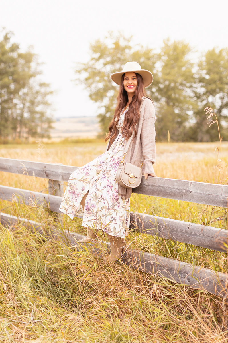 Early Autumn 2020 Lookbook | Country Checks | Smiling brunette woman wearing a botanical print button down midi dress, a Chloe Tess Bag in Grey, knee high suede pointed toe boots and a taupe flat brimmed hat next to an weathered fence in the prairies | Boho Fall 2020 Outfit Ideas | Top Fall 2020 Trends | How to Style Midi Dresses for Fall | Bohemian Fall outfit Ideas | How to Wear Florals in Fall | Cottagecore Fall Outfit Ideas | Calgary Alberta Fashion & Lifestyle Blogger // JustineCelina.com