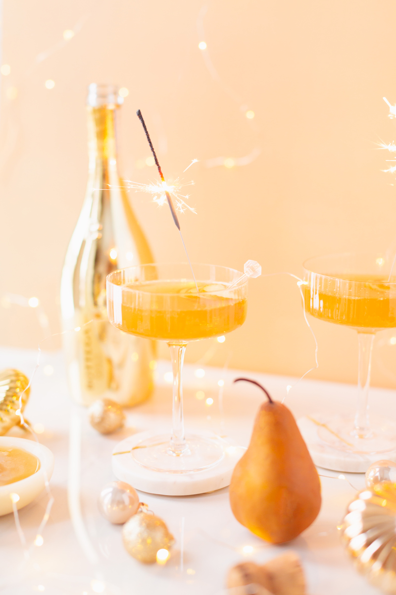 Gilded Vanilla Pear Sparkler | A glitzy, French 75 inspired New Years Eve cocktail featuring 24 karat gold infused gin, Brut Prosecco, Italian vanilla liqueur, lemon juice and Honeyed Vanilla Pear Syrup | Best NYE 2020 cocktails | How to Make sparkling NYE cocktails at home | Champagne cocktail recipe | Champagne Christmas drinks | New Years Eve Sparklers | Modern Refined Sugar Free French 75 | NYE Cocktail Party Recipes | Calgary Creative Lifestyle & Cocktail Blogger // JustineCelina.com