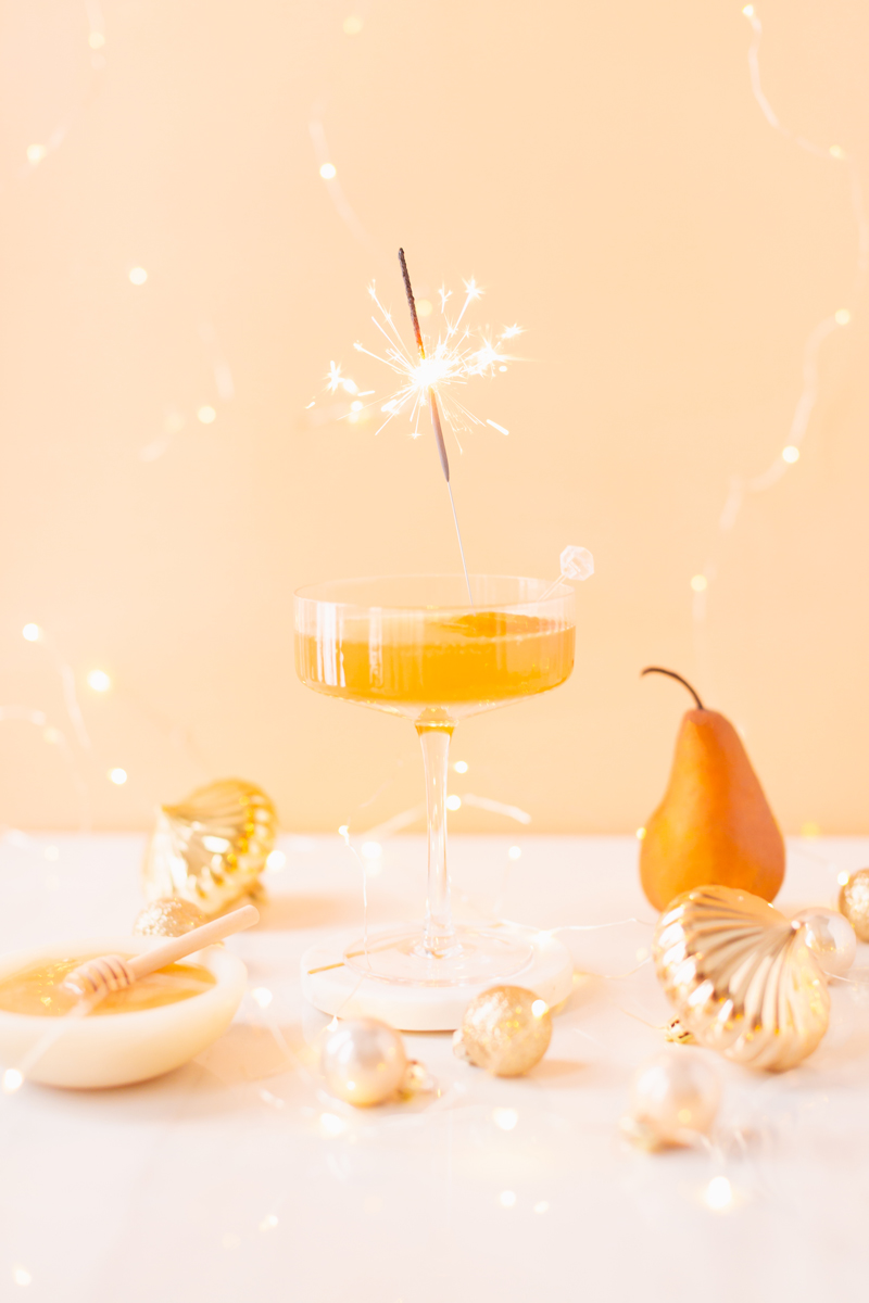 Gilded Vanilla Pear Sparkler | A glitzy, French 75 inspired New Years Eve cocktail featuring 24 karat gold infused gin, Brut Prosecco, Italian vanilla liqueur, lemon juice and Honeyed Vanilla Pear Syrup | Best NYE 2020 cocktails | How to Make sparkling NYE cocktails at home | Champagne cocktail recipe | Champagne Christmas drinks | New Years Eve Sparklers | Modern Refined Sugar Free French 75 | NYE Cocktail Party Recipes | Calgary Creative Lifestyle & Cocktail Blogger // JustineCelina.com