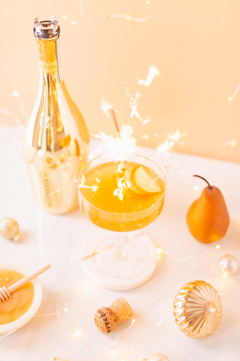 Gilded Vanilla Pear Sparkler | A glitzy, French 75 inspired New Years Eve cocktail featuring 24 karat gold infused gin, Bottega Gold Prosecco, Italian vanilla liqueur, lemon juice and Honeyed Vanilla Pear Syrup | Best NYE 2020 cocktails | How to Make sparkling NYE cocktails at home | Champagne cocktail recipe | Champagne Christmas drinks | New Years Eve Sparklers | Refined Sugar Free French 75 | NYE Cocktail Party Recipes | Calgary Creative Lifestyle & Cocktail Blogger // JustineCelina.com