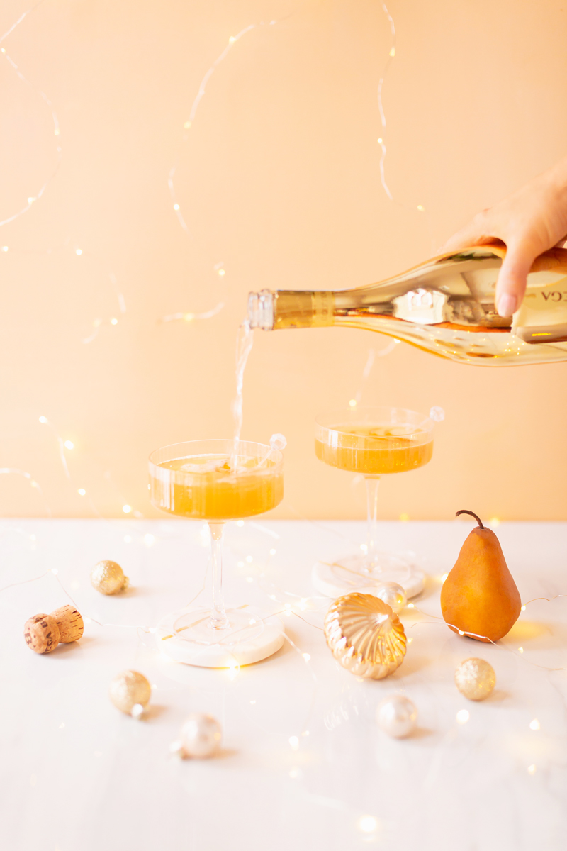 Gilded Vanilla Pear Sparkler | A glitzy, French 75 inspired New Years Eve cocktail featuring 24 karat gold infused gin, Brut Prosecco, Italian vanilla liqueur, lemon juice and Honeyed Vanilla Pear Syrup | Best NYE 2020 cocktails | How to Make sparkling NYE cocktails at home | Champagne cocktail recipe | Champagne Christmas drinks | New Years Eve Sparklers | Modern Refined Sugar Free French 75 | NYE Cocktail Party Recipes | Calgary Creative Lifestyle & Cocktail Blogger // JustineCelina.com