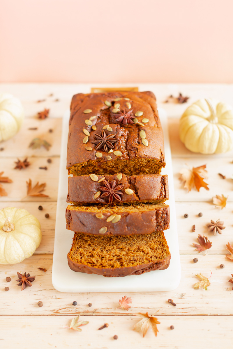 Gluten Free Mapled Pumpkin Chai Bread | Sliced Pumpkin Bread on a Marble Serving Board, served on 2 pink plates with gold forks and a chai latte | Chai Spice Bread styled with spices and white mini pumpkins arranged on blush pink barn board backdrop | Easy Pumpkin Bread | Moist Pumpkin Bread | The Best Gluten Free Fall Baking Recipes | No Sugar Pumpkin Bread | Maple Syrup Pumpkin Bread | Pumpkin Bread Cake | Healthy Pumpkin Bread | Calgary Plant Based Food Blogger // JustineCelina.com