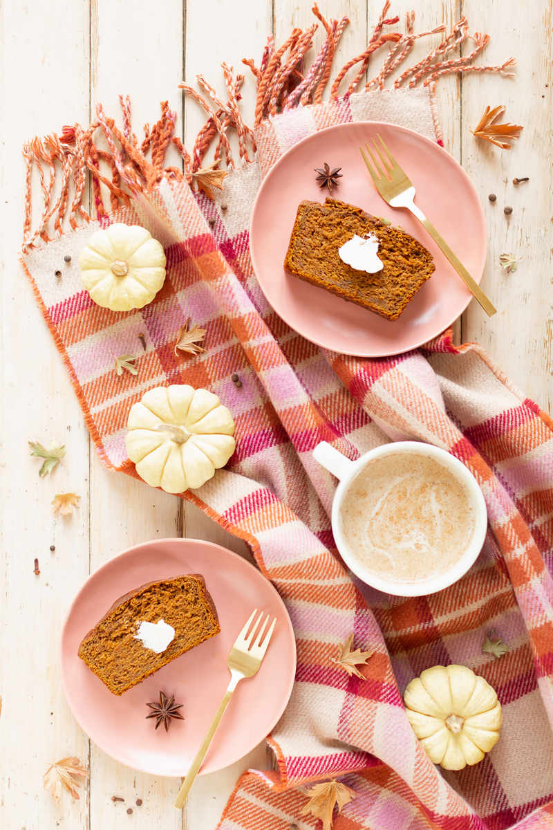 Gluten Free Mapled Pumpkin Chai Bread | Sliced Pumpkin Bread on a Marble Serving Board, served on 2 pink plates with gold forks and a chai latte | Chai Spice Bread styled with spices and white mini pumpkins arranged on blush pink barn board backdrop | Easy Pumpkin Bread | Moist Pumpkin Bread | The Best Gluten Free Fall Baking Recipes | No Sugar Pumpkin Bread | Maple Syrup Pumpkin Bread | Pumpkin Bread Cake | Healthy Pumpkin Bread | Calgary Plant Based Food Blogger // JustineCelina.com