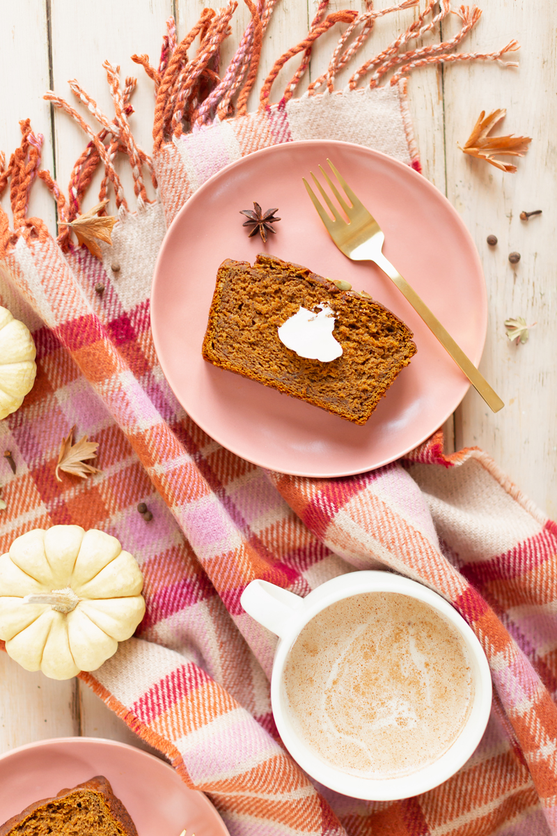 Gluten Free Mapled Pumpkin Chai Bread | Sliced Pumpkin Bread on a Marble Serving Board, served on 2 pink plates with gold forks and a chai latte | Chai Spice Bread styled with spices and white mini pumpkins arranged on blush pink barn board backdrop | Easy Pumpkin Bread | Moist Pumpkin Bread | The Best Gluten Free Fall Baking Recipes | No Sugar Pumpkin Bread | Maple Syrup Pumpkin Bread | Pumpkin Bread Cake | Healthy Pumpkin Bread | Calgary Plant Based Food Blogger // JustineCelina.com