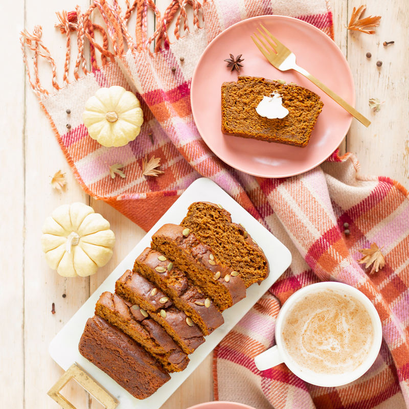 Gluten Free Mapled Pumpkin Chai Bread | Sliced Pumpkin Bread on a Marble Serving Board, served on 2 pink plates with gold forks and a chai latte | Chai Spice Bread styled with spices and white mini pumpkins arranged on blush pink barn board backdrop | Easy Pumpkin Bread | Moist Pumpkin Bread | The Best Gluten Free Fall Baking Recipes | No Sugar Pumpkin Bread | Maple Syrup Pumpkin Bread | Pumpkin Bread Cake | Healthy Pumpkin Bread | Calgary Plant Based Food Blogger // JustineCelina.com