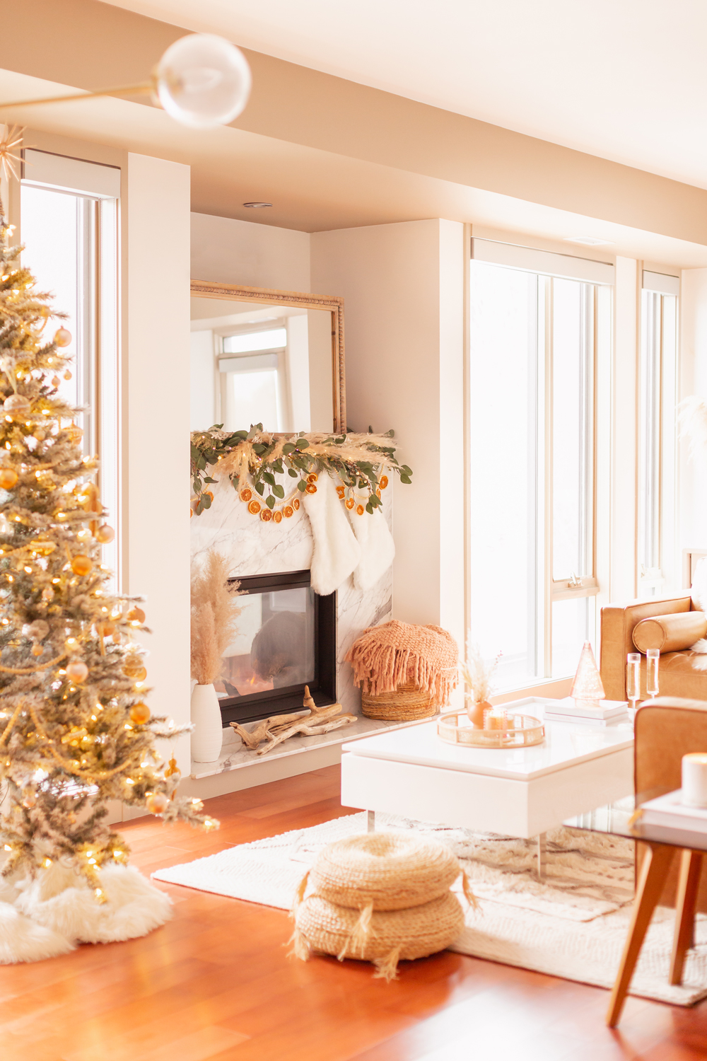 Mid Century Meets Boho Holiday Decor 2021 | Bright & airy Mid Century Modern Living Room with a Flocked Christmas Tree and Sputnik Metallic Tree Topper | Boho eucalyptus garland with pampas grass, fresh cedar, bleached Italian ruscus and a beaded dried orange garland | Boho Christmas Decorating Ideas for Apartments | Flocked Christmas Tree with Wood Garland and Boho Ornaments | Holiday Home Tour | Boho Chic Christmas Decor | Glam neutral holiday decor | Boho Christmas Tree // JustineCelina.com