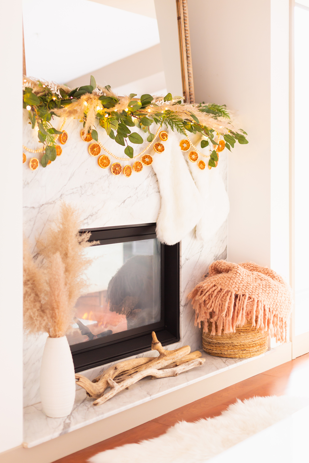 Mid Century Meets Boho Holiday Decor | Bright airy Mid Century Modern Living Room with a boho eucalyptus garland with pampas grass, fresh cedar, bleached Italian ruscus and a beaded dried orange garland | Boho Christmas Decorating Ideas for Apartments | Boho Holiday Fireplace Decor | DIY Orange Slice Garland | Bohemian Holiday Home Tour 2021 | Boho Chic Christmas Decor | Glam neutral holiday decor | Warm toned Holiday decor | Fun Holiday Decor | Dried Fruit Holiday Decor // JustineCelina.com