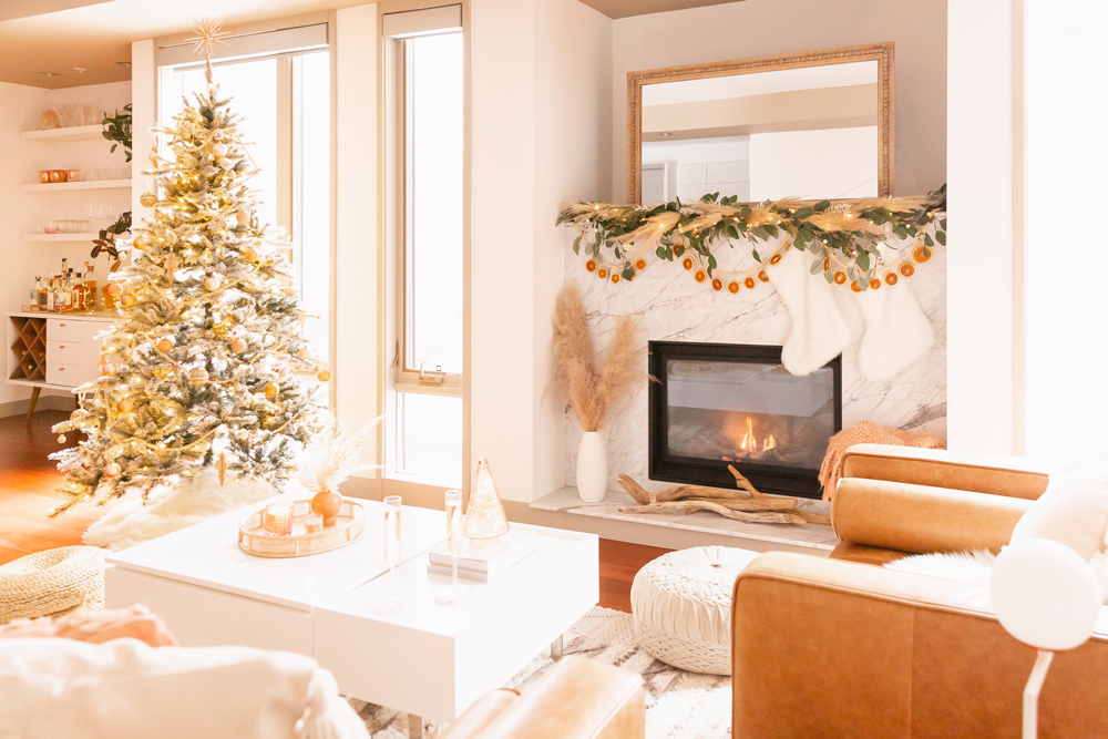Mid Century Meets Boho Holiday Decor 2021 | Bright & airy Mid Century Modern Living Room with a Flocked Christmas Tree and Sputnik Metallic Tree Topper in front of floor to ceiling windows and a marble fireplace | Eucalyptus garland with pampas grass and dried orange slices | Boho Christmas Decorating Ideas for Apartments | Flocked Christmas Tree with Wood Garland and Boho Ornaments | Holiday Home Tour | Boho Chic Christmas Decor | Neutral holiday decor | Boho Christmas Tree // JustineCelina.com