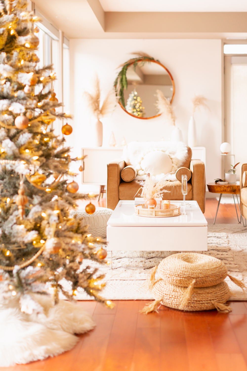 Mid Century Meets Boho Holiday Decor | Bright and airy Mid Century Modern Living Room with a Flocked Christmas Tree and Caramel Leather Couches | Mid Century Modern Christmas Tree Skirt | Boho Christmas Decorating Ideas for Apartments | Flocked Christmas Tree with Wood Garland, Metallic and Wood Ornaments | Bohemian Holiday Home Tour 2021 | Boho Chic Christmas Decor | Glam neutral holiday decor | Warm Holiday Decor | Pampas Grass Holiday Arrangement | Boho Christmas Tree // JustineCelina.com
